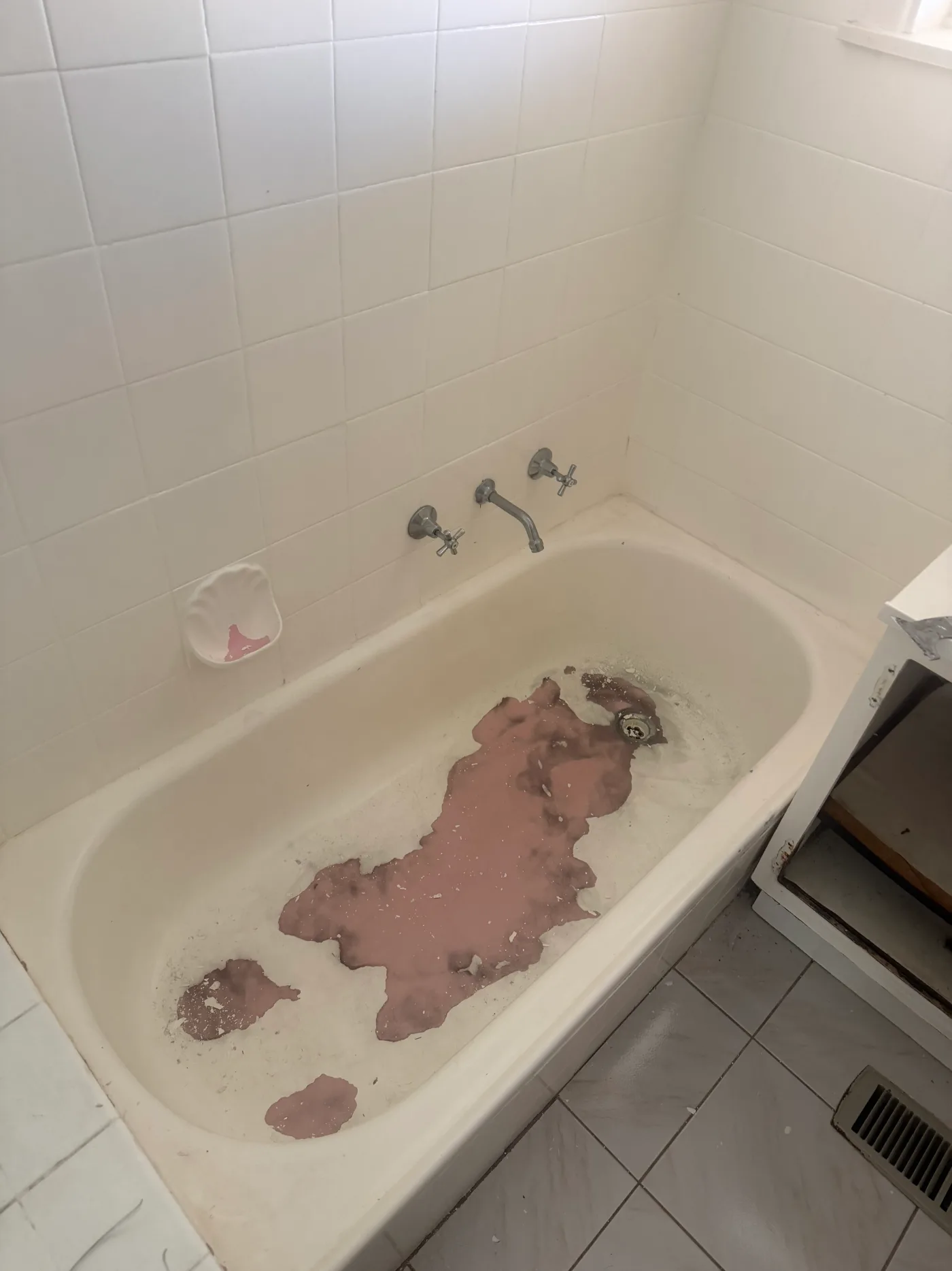 A Moorabbin bathtub before resurfacing, its original coating worn through to the pink undercoat across the base