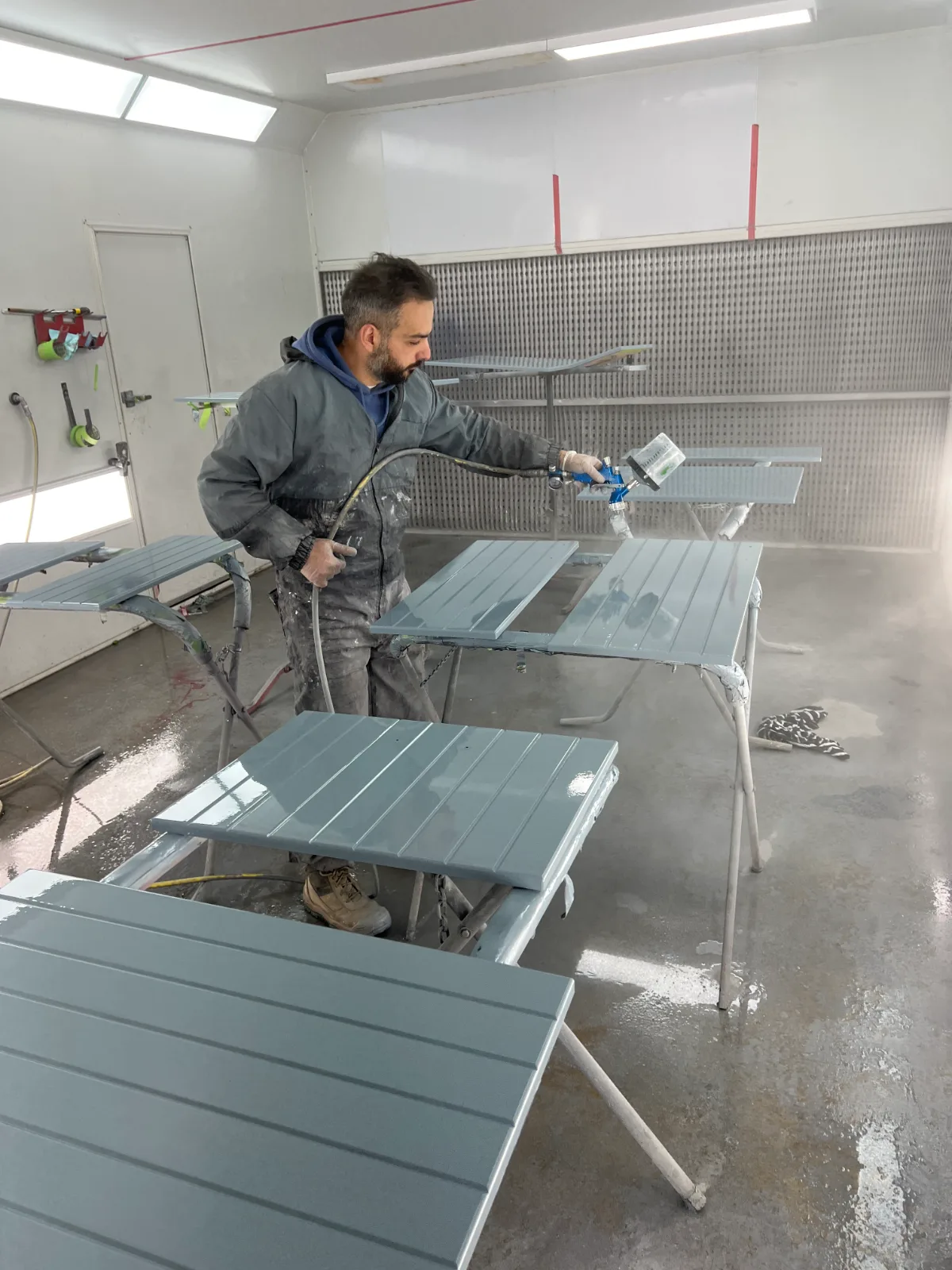 Spray gun laying an even coat across a kitchen cabinet door in the booth