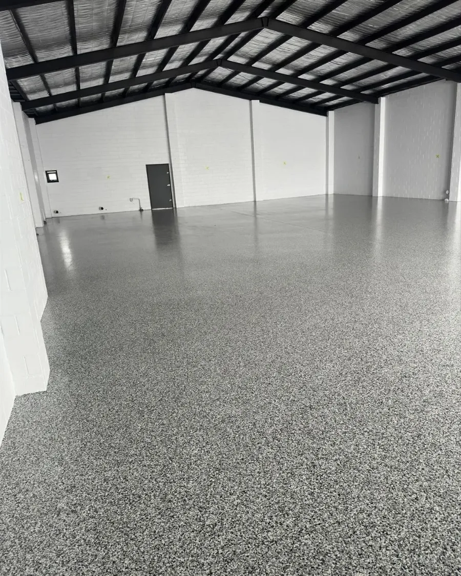 Grey and black decorative epoxy flake floor finished by Jetblack Painting in the same Melbourne warehouse