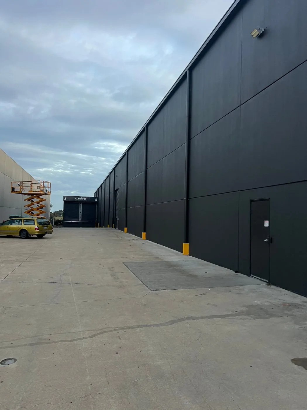 Industrial building painting in progress with access equipment by Jetblack Painting