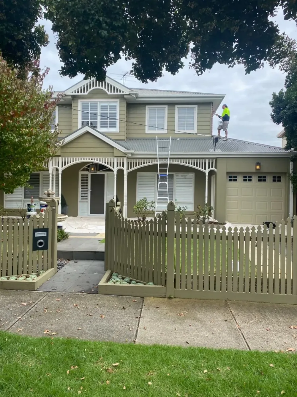 Roof restoration in progress on a weatherboard home, with a Jetblack Painting painter working from the ridge