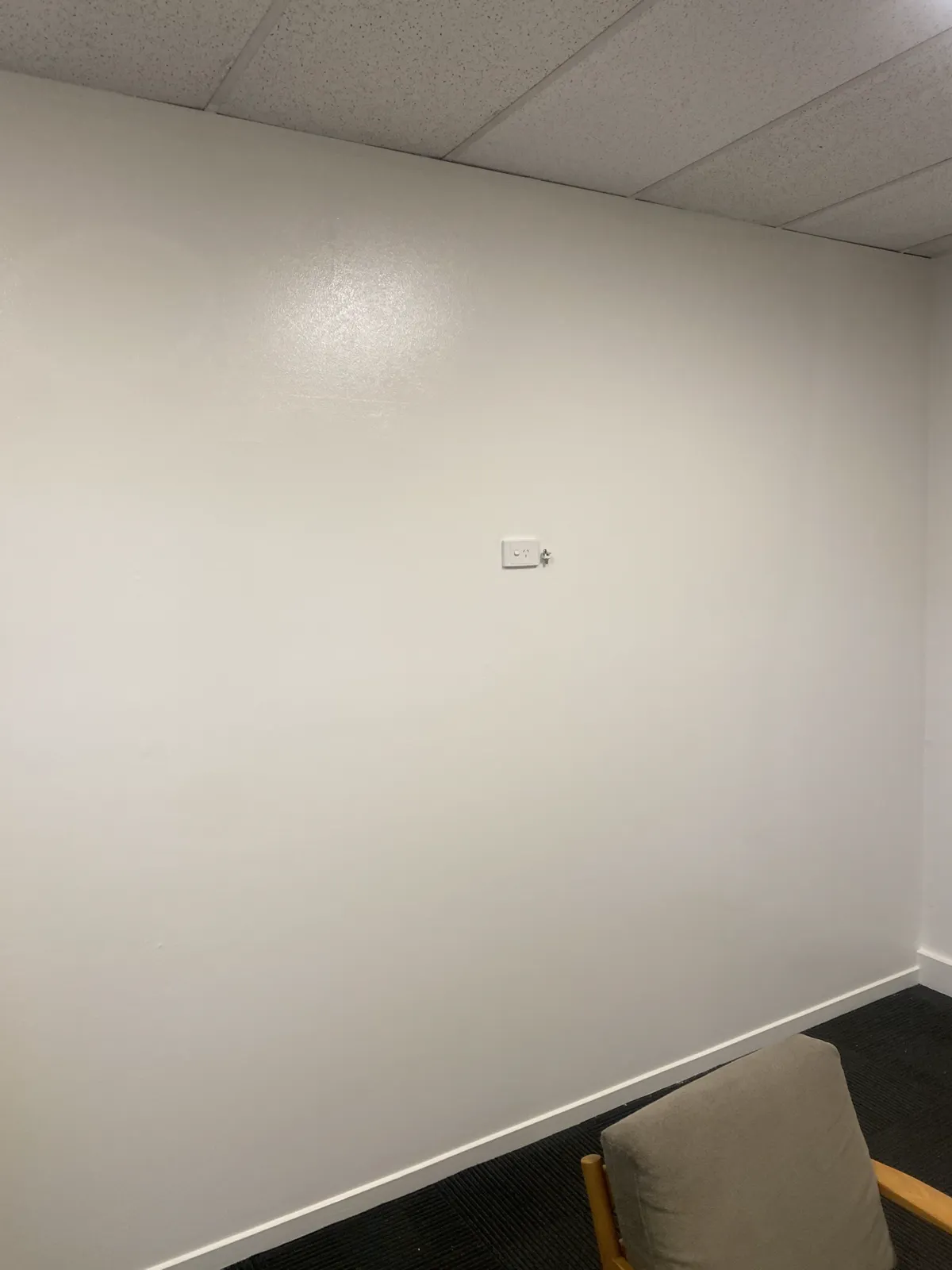 Office wall in Brighton on a commercial repaint, white walls and skirting under a suspended ceiling, with carpet tiles and an office chair in the corner