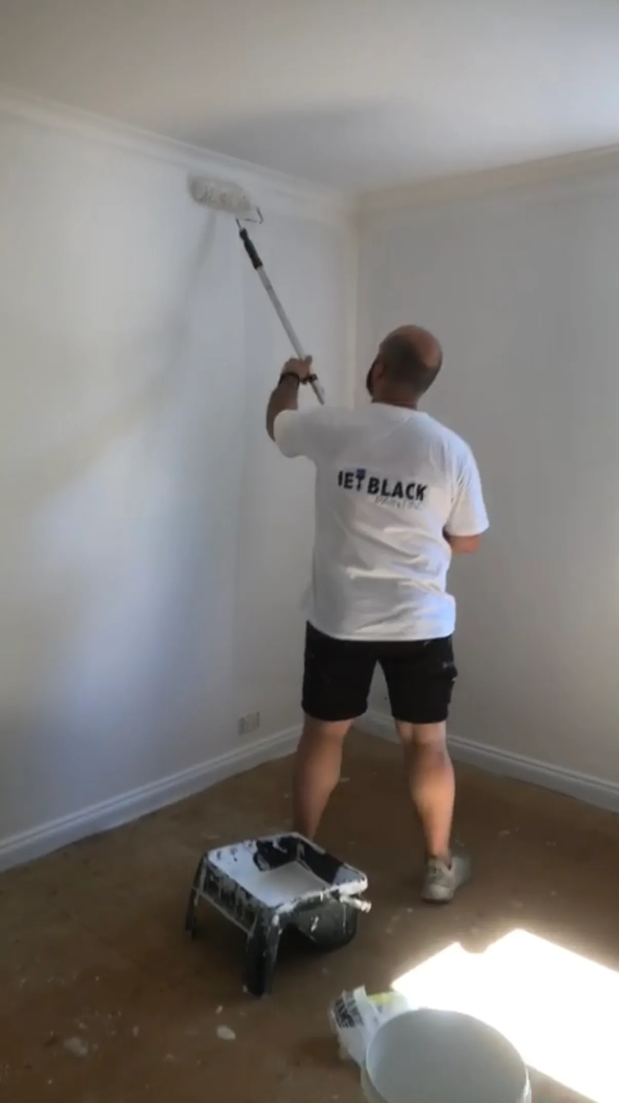 Jimmy Demirci of Jetblack Painting rolling a wall with an extension pole during an interior repaint in Brighton