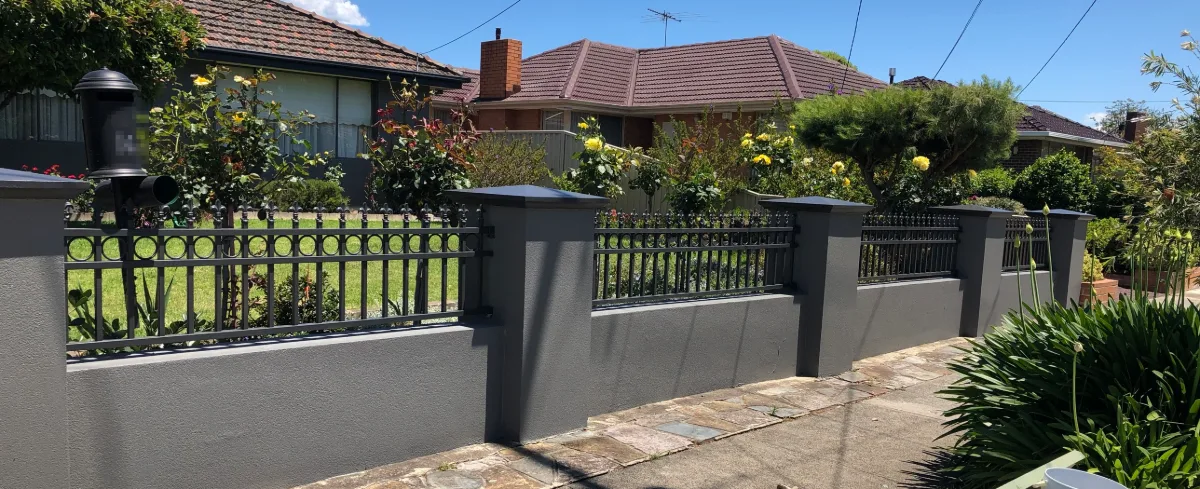 Rendered front fence in Burwood, near Box Hill, after painting, with charcoal grey pillars and plinth walls, darker capping and black decorative metal panels