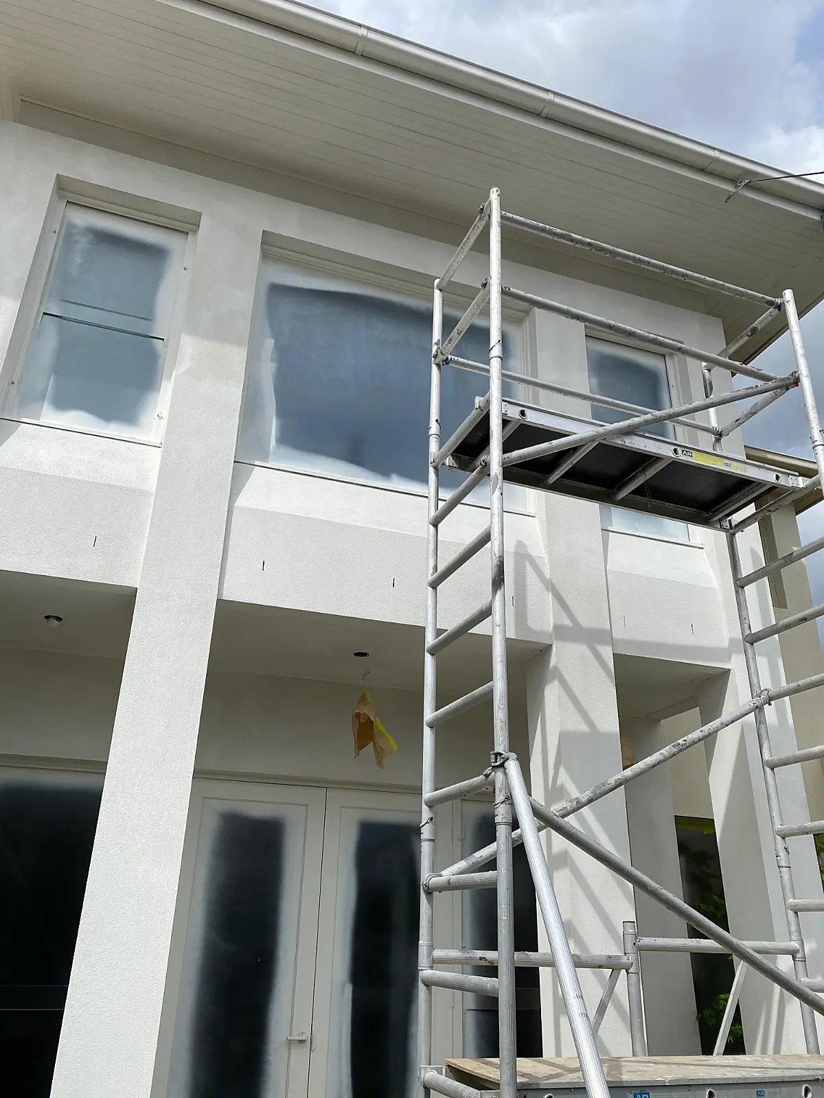 Scaffolding and fully masked windows on a Caulfield render exterior during painting
