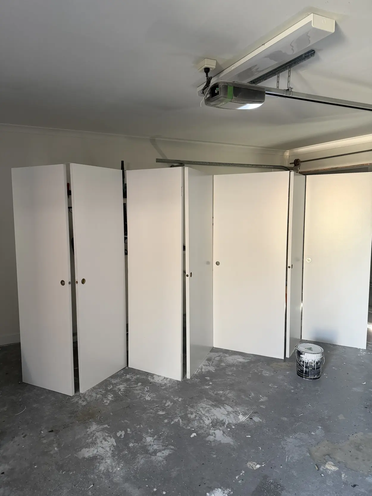 A row of internal doors from a Cheltenham home standing on edge in a garage after painting, finished in white with the handles and latches removed