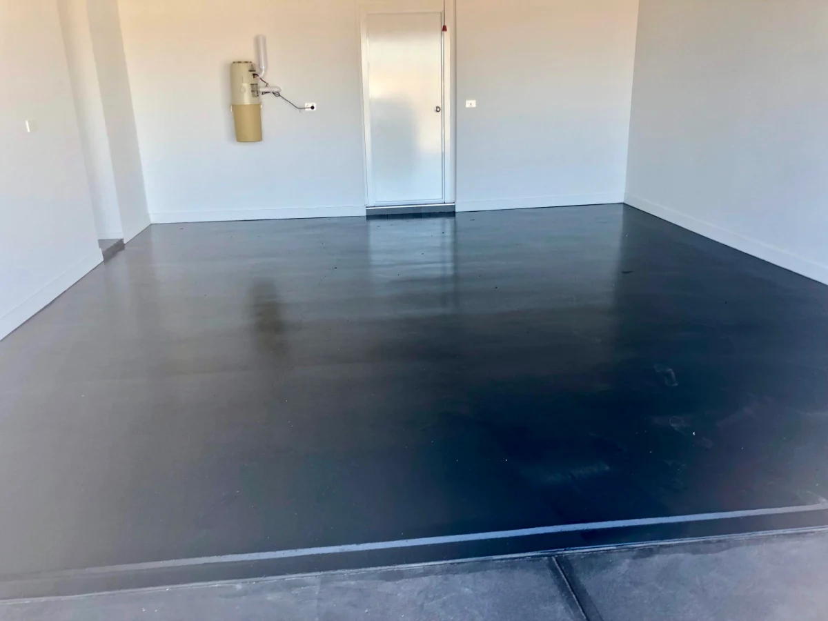 The same Clyde garage after a solid charcoal epoxy floor coating, cut clean along the white skirting