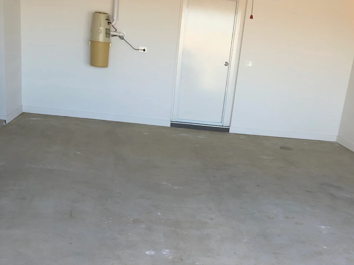Double garage in a new Clyde home before its epoxy floor, with bare grey concrete marked by scuffs and paint spots