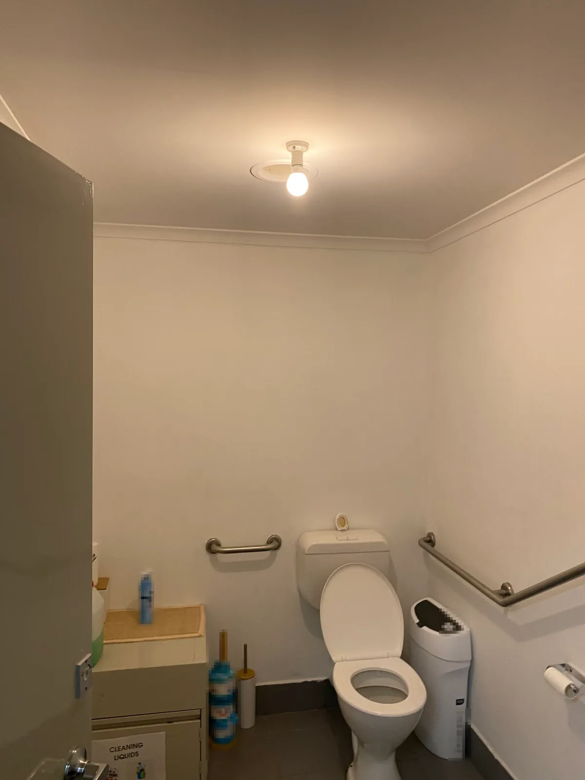 Accessible toilet in a commercial office in Dandenong after interior painting, with white walls, ceiling and cornice, grab rails and a dark skirting tile