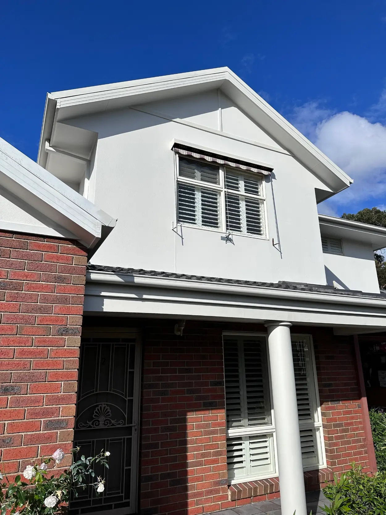 Rendered upper storey and gable on a Dingley Village home after painting, finished in white above the original red brick and a white portico column