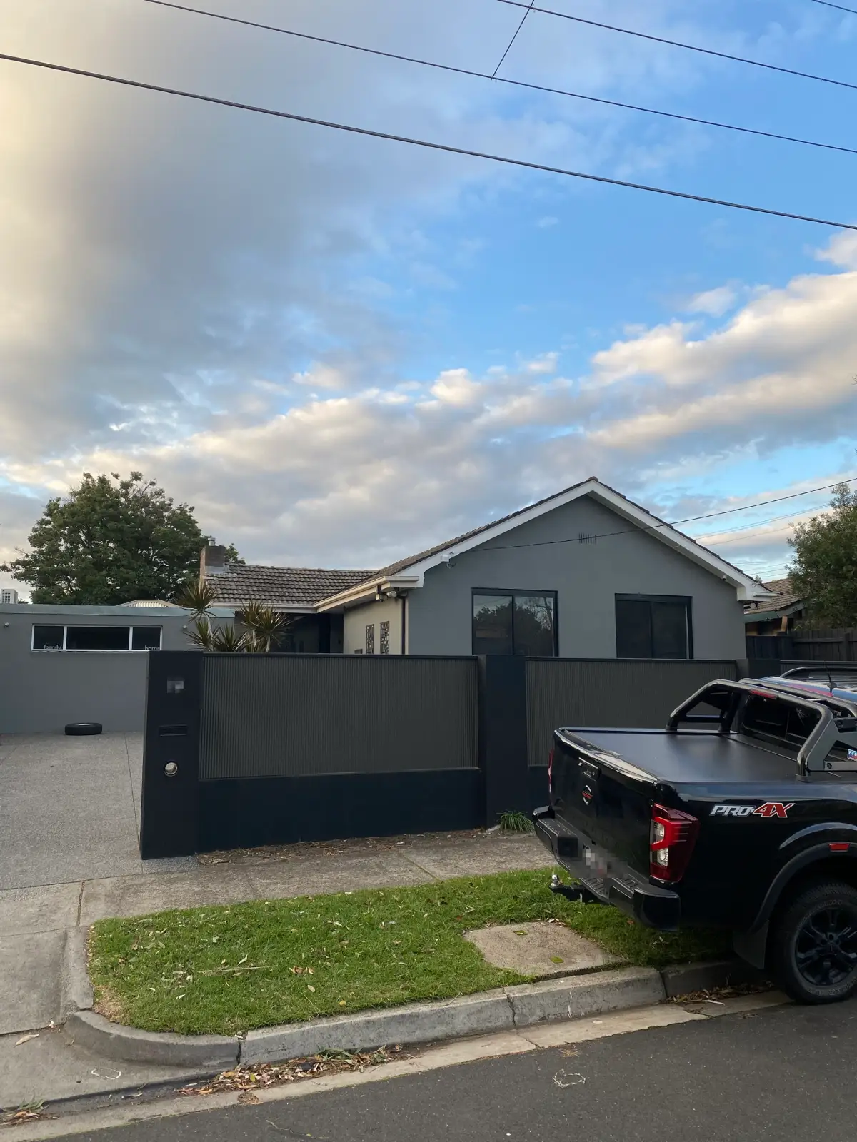 Street frontage of a rendered Dingley Village home after painting, with the house, eaves and a corrugated boundary fence all carried in tones of grey and charcoal