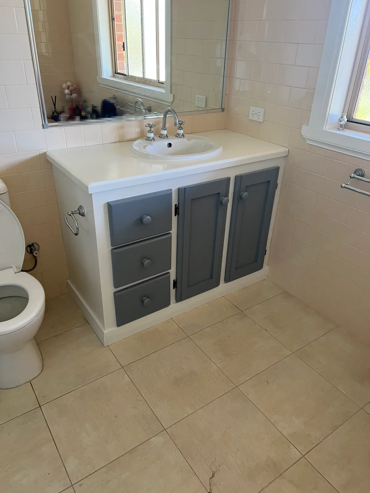 Bathroom vanity in a Dromana home after repainting, white carcass and benchtop with grey panelled doors and drawers and grey knobs, beside cream wall tiles