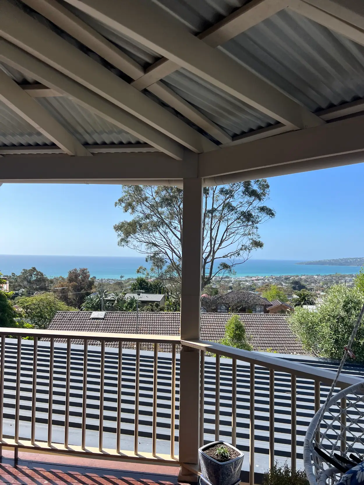 Elevated verandah on a Dromana home after a full exterior repaint, with painted timber posts, beams and balustrade framing a view over Port Phillip Bay
