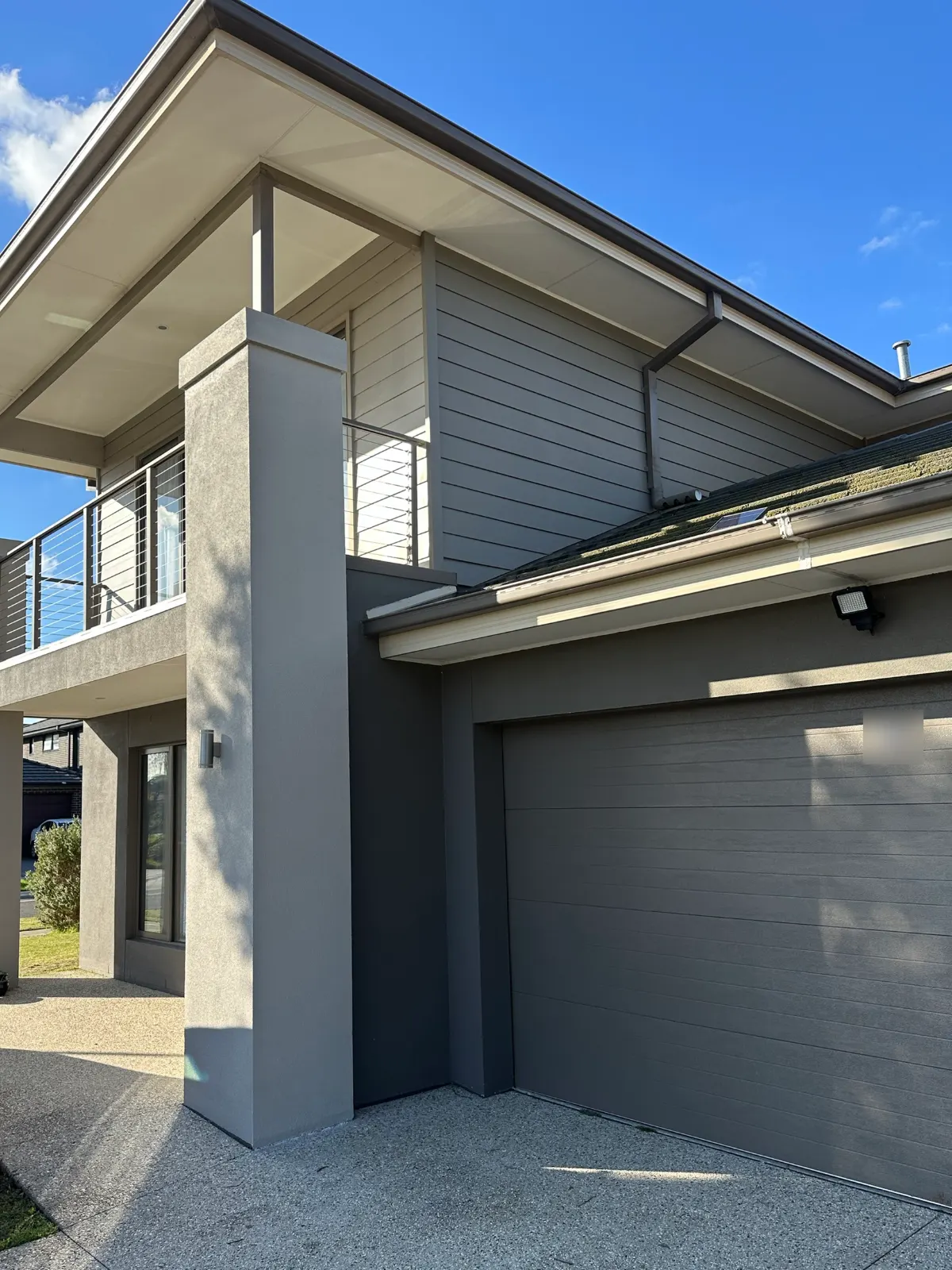 Contemporary two-storey Hawthorn home after an exterior repaint, with grey rendered pillars and balcony, paler grey cladding on the upper storey and a darker grey base around the garage