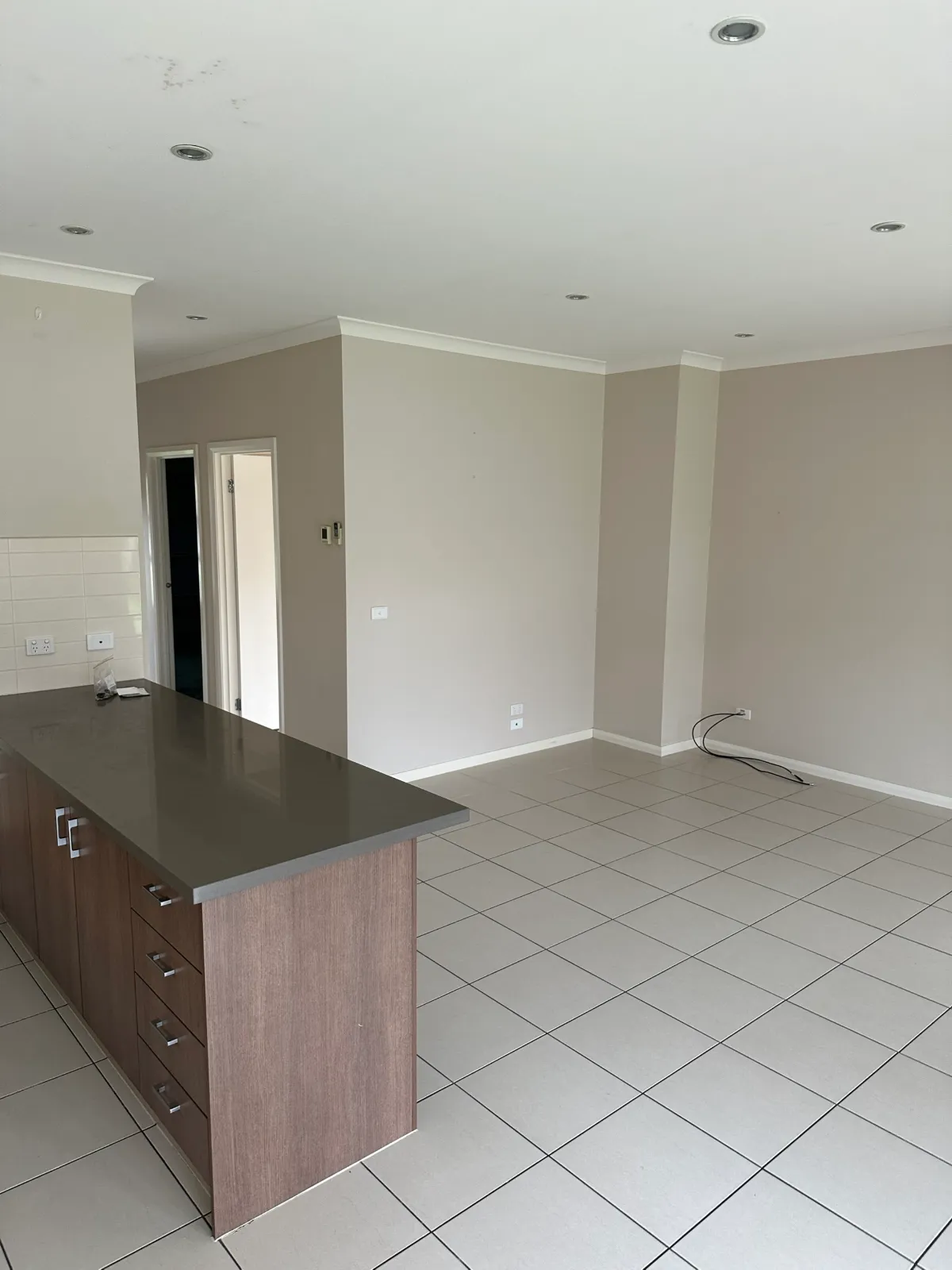 Open-plan living area and kitchen island in a Kew home before an interior repaint, with water stains on the ceiling and marks on the walls