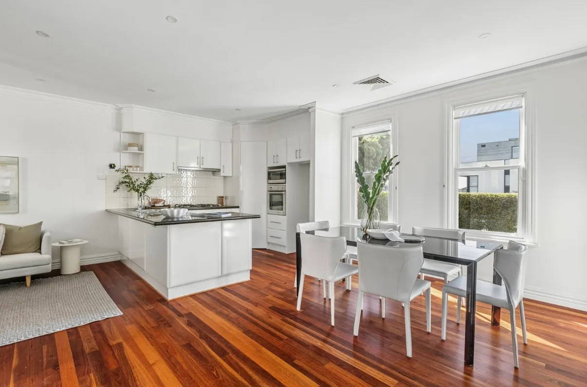 Kitchen and dining area of the same Malvern home after the pre-sale repaint, white walls, cornices and window frames above timber floors