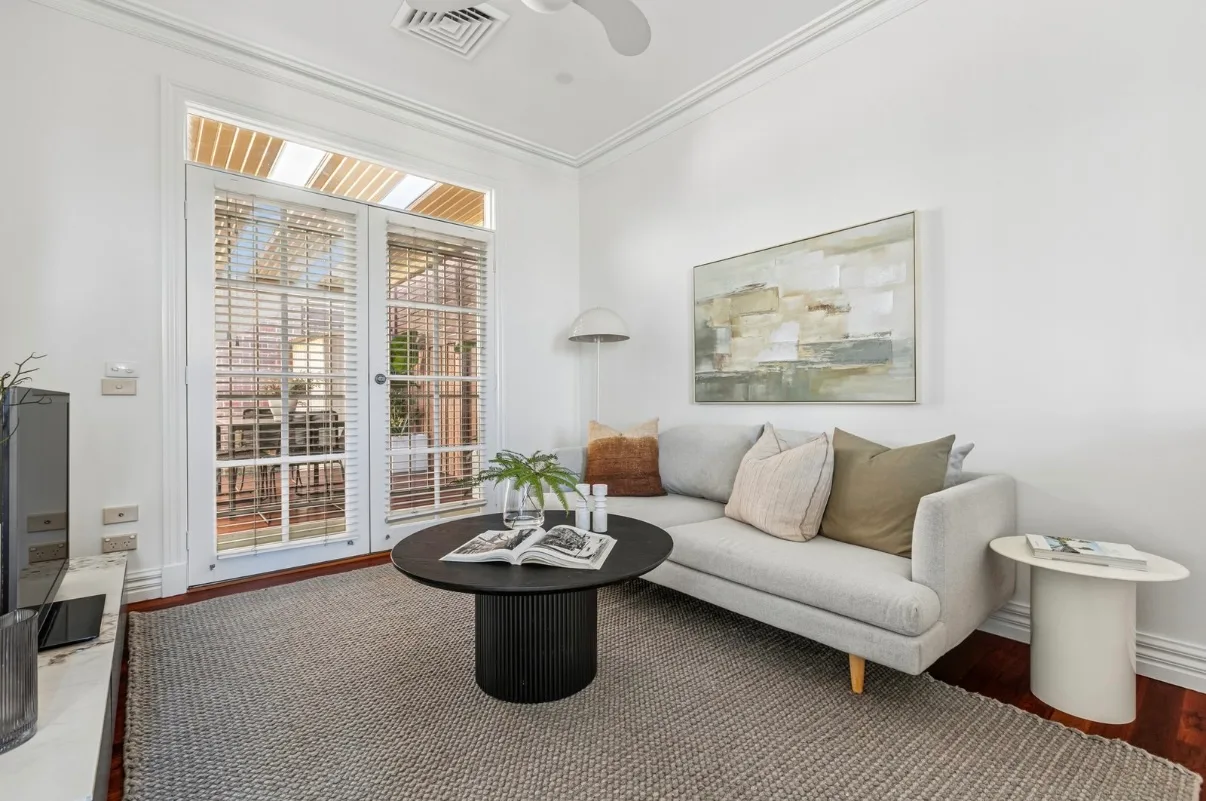 The same Malvern family room after the pre-sale repaint, white cornice, walls and French door frames above timber floors
