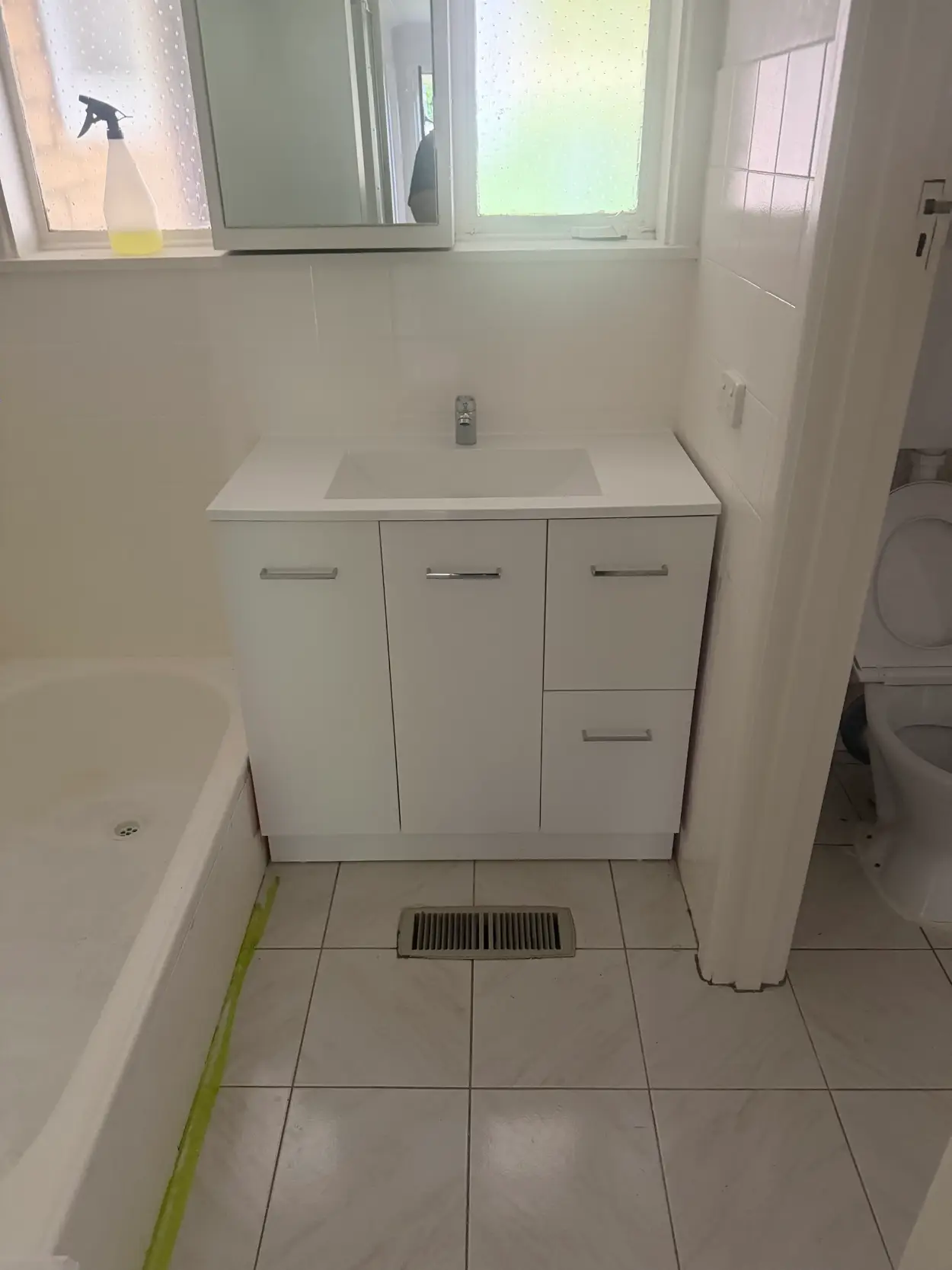 The same Moorabbin bathroom after the vanity was replaced, with a white flat-panel unit, a new basin and masking tape still along the bath edge