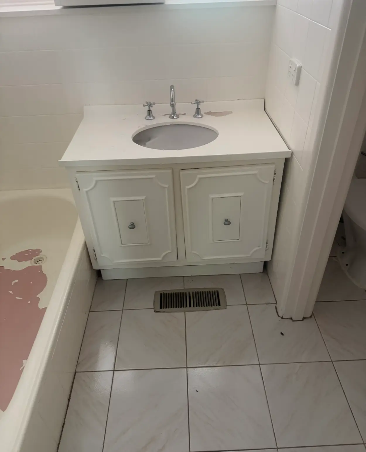 Bathroom vanity in a Moorabbin home before replacement, its moulded doors and benchtop worn with the finish chipped away to a pink undercoat