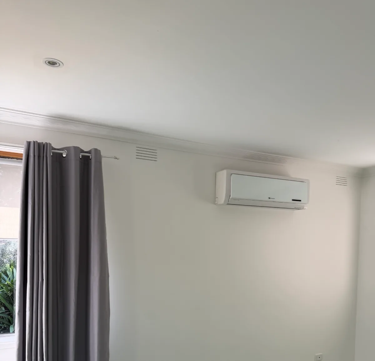 Lounge wall in the Mordialloc rental after an interior repaint, painted white around the split-system air conditioner and vents