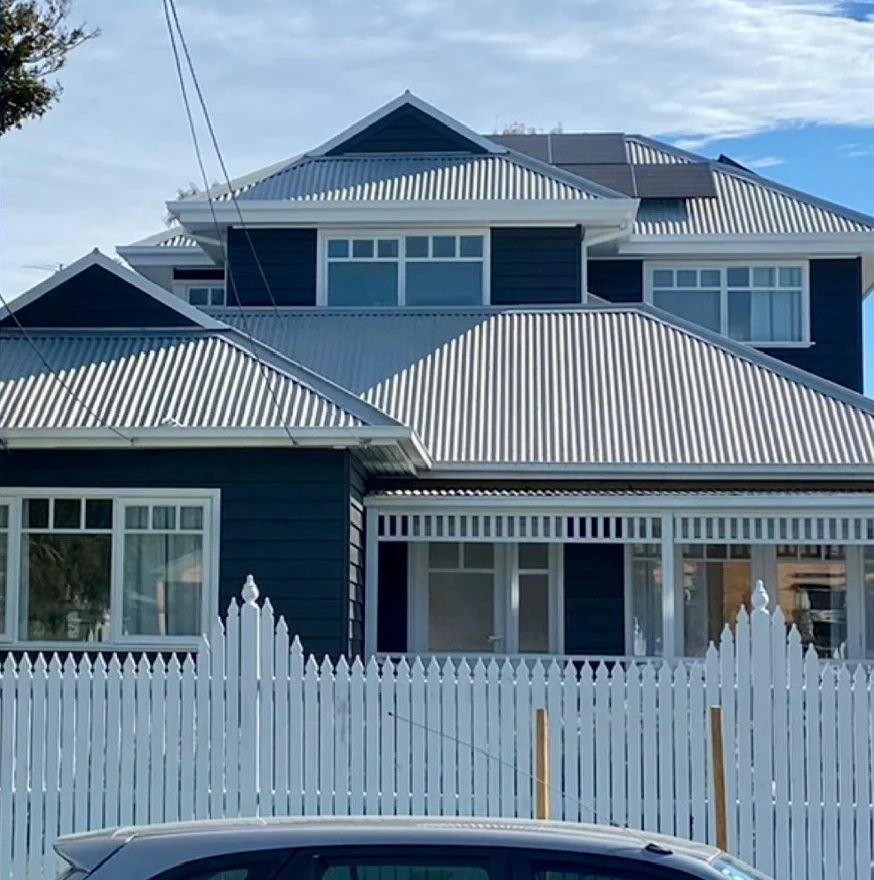 Weatherboard home in Mordialloc after an exterior repaint, with charcoal boards and white eaves, fretwork and window frames