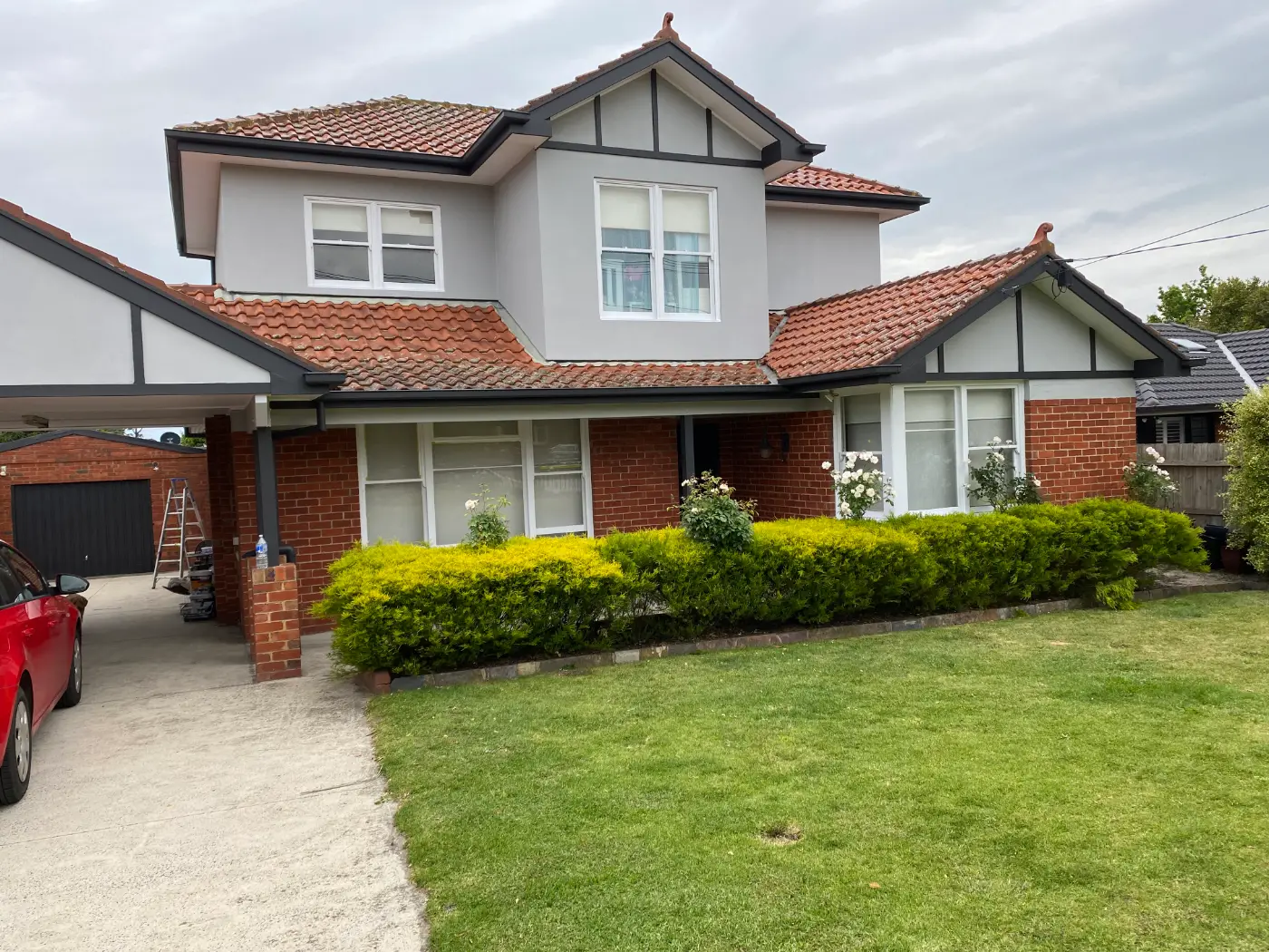 Tudor-style Murrumbeena home after an exterior repaint, render in Dulux Silkwort with Dulux Monument picked out through the half-timbering, fascias and gutters, above original red brick and a terracotta tile roof