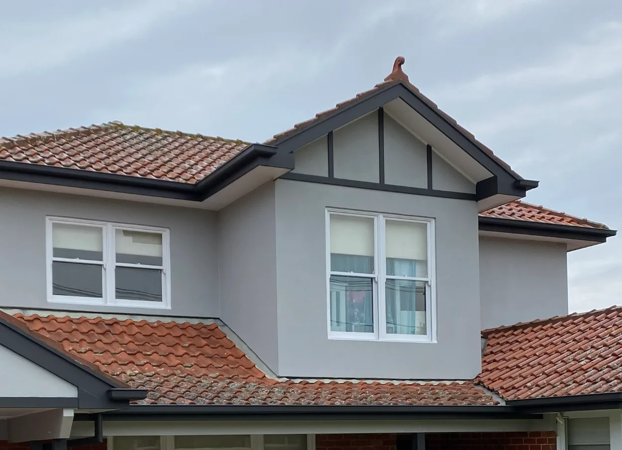 The same upper storey of the Murrumbeena home after repainting, render in Dulux Silkwort with the half-timbering, fascia and gutters in Dulux Monument