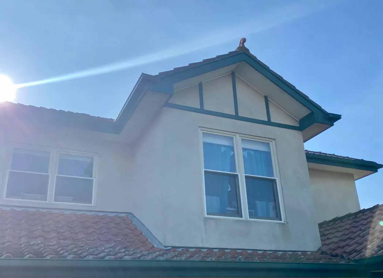 Upper storey of the same Tudor-style Murrumbeena home before repainting, with cream render and the half-timbering, fascia and gutters in dark green