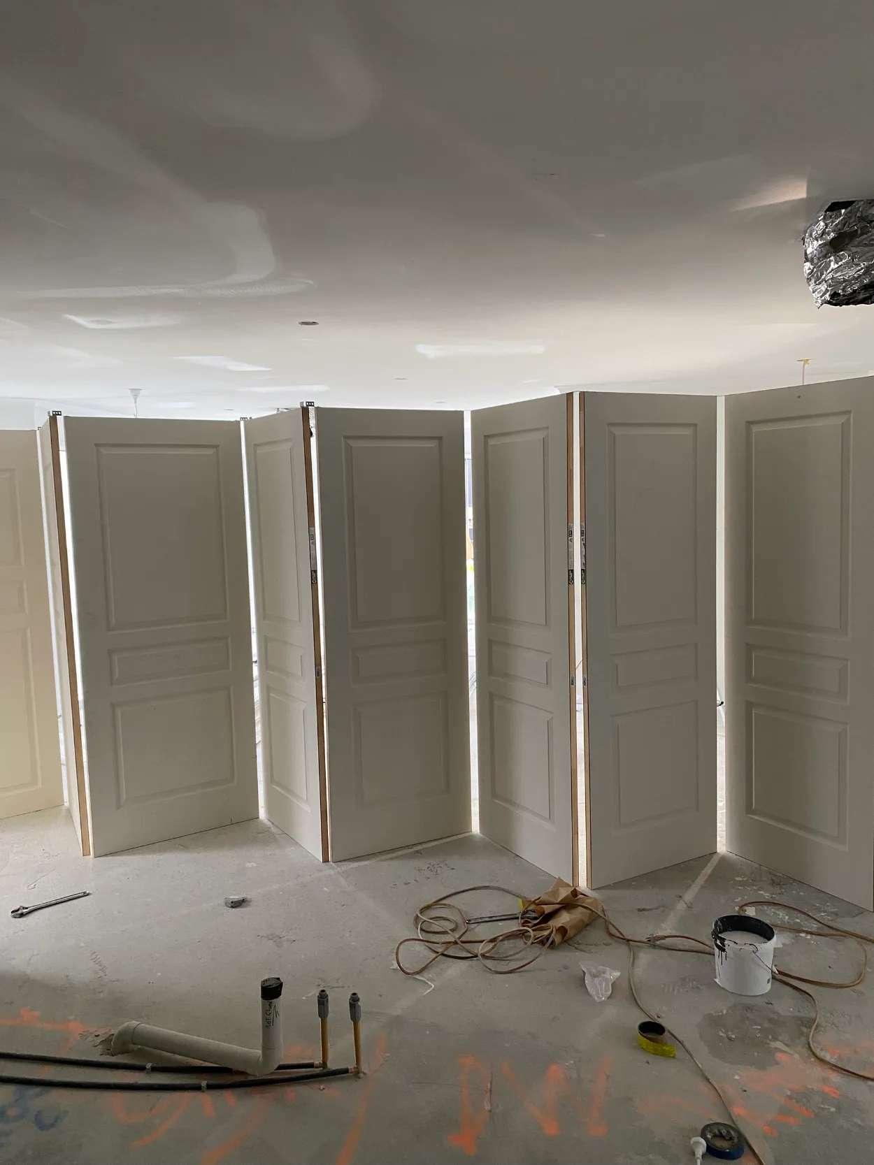A run of new three-panel doors stood upright across an unfinished room in a Narre Warren build, with a set plaster ceiling above a bare concrete floor