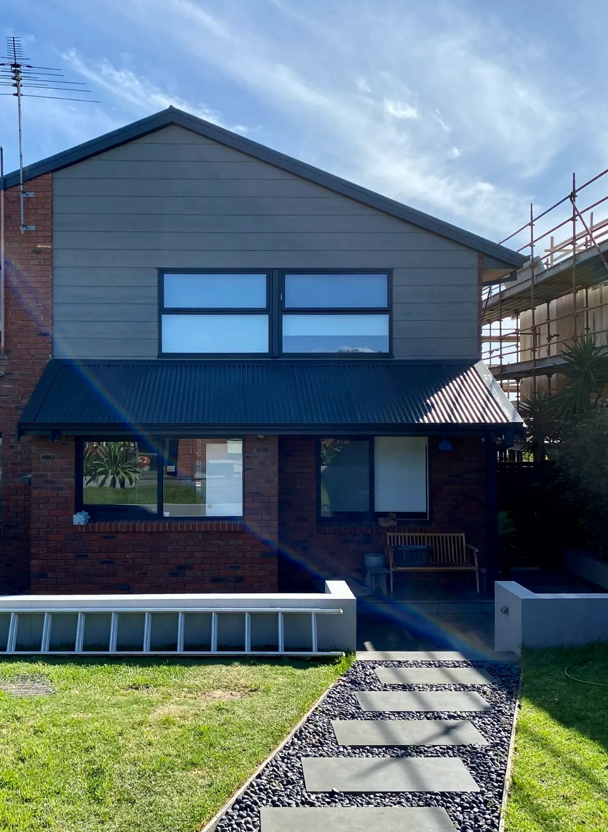 Two-storey Parkdale home after painting, with the gable cladding, fascias, gutters and window frames in charcoal above unpainted red brick