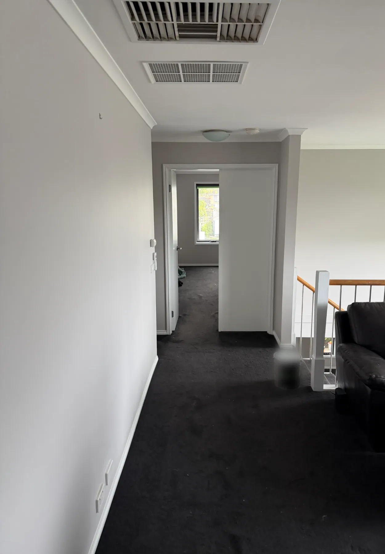 Upstairs landing of a two-storey Parkdale home during an interior repaint, with light walls and ceiling, white skirting and door frames, a hallway leading to a bedroom and the stair balustrade on the right