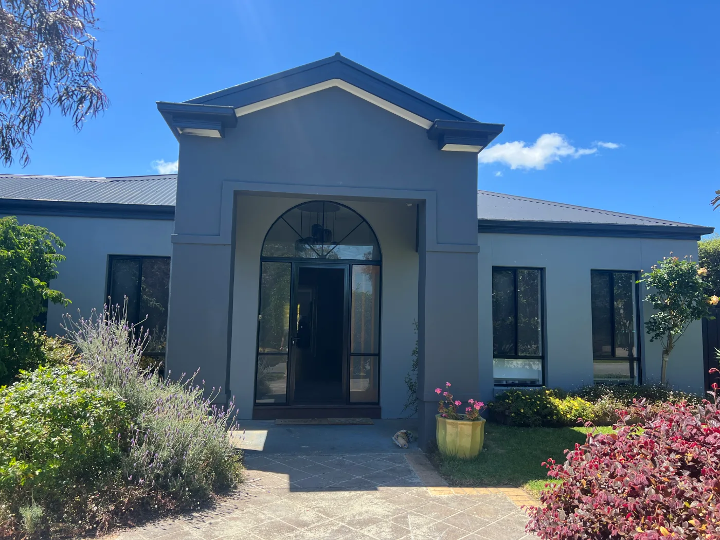 The same Safety Beach home after repainting, with grey render and a dark charcoal roof