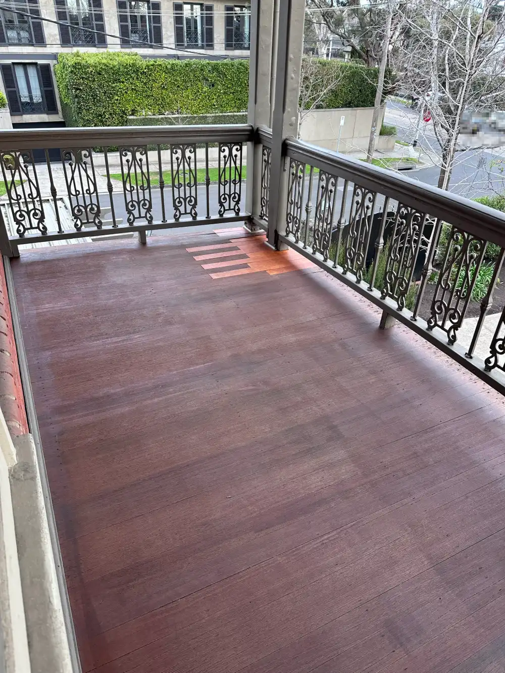 Cast-iron lace balustrade on the balcony of a period Stonnington home, with the timber decking recoated and a run of replacement boards sitting lighter than the rest