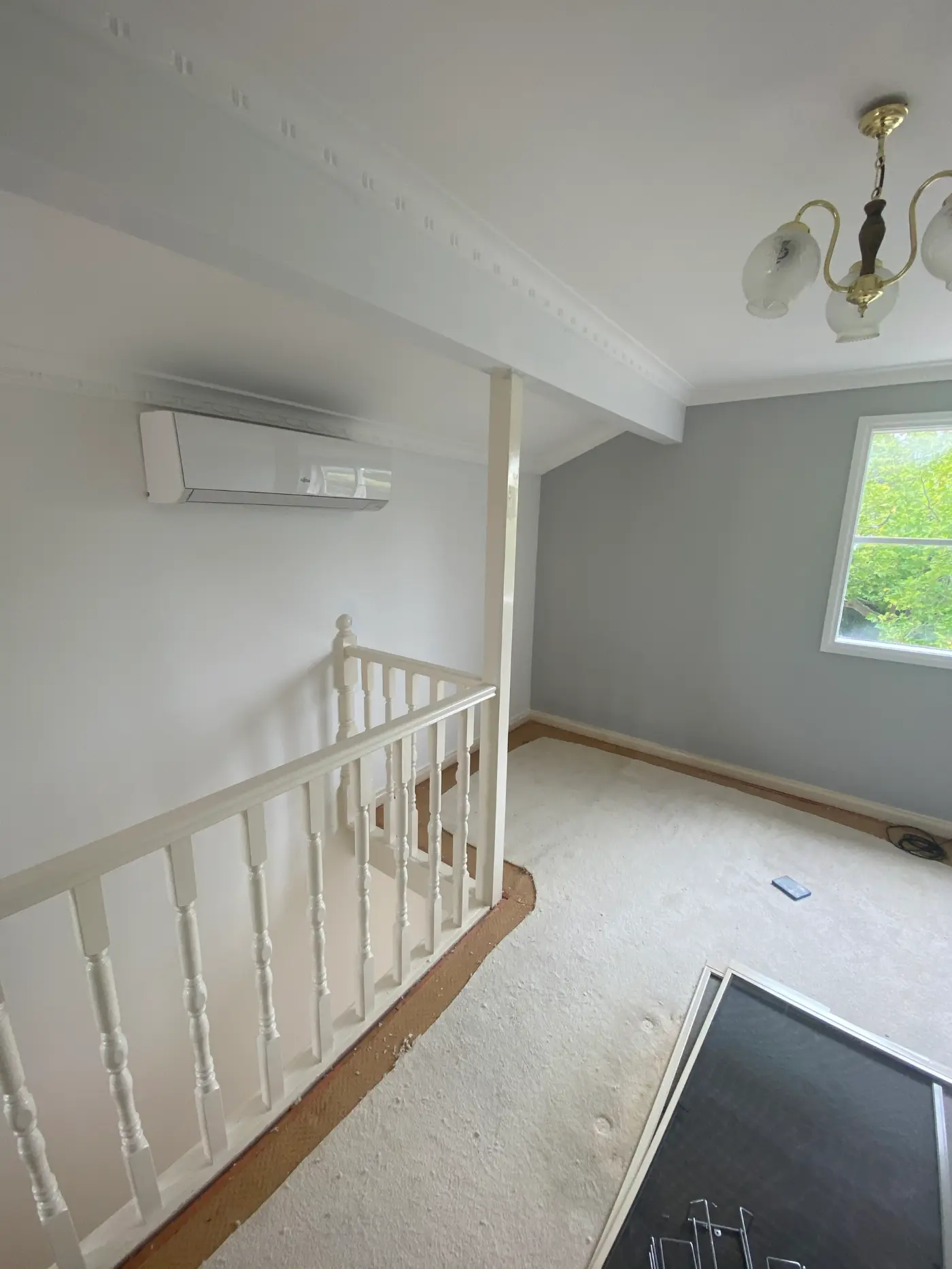 Upstairs landing in a Toorak home after repainting, with grey-blue walls, white ceiling and cornice, and a white turned-timber stair balustrade