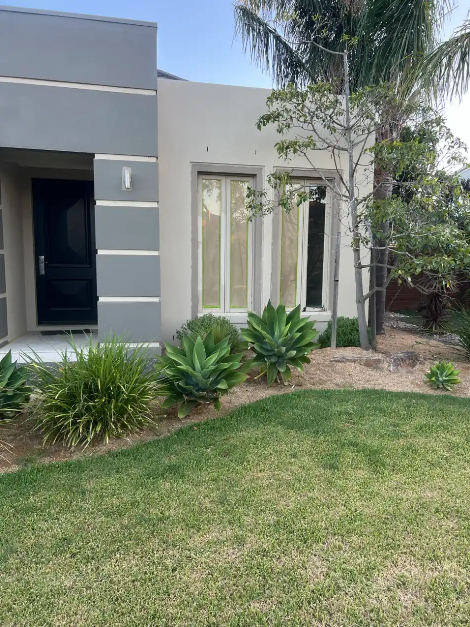 Wider view of a rendered Waterways street elevation after painting, the darker grey entry block set against the paler wall running back to the garden